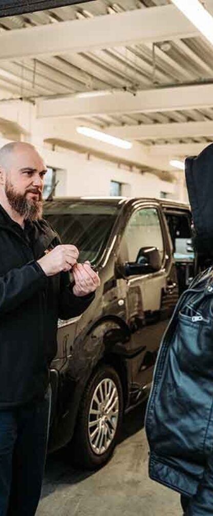 Image of autolocksmiths talking in a garage.
