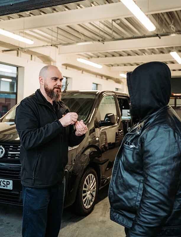 Image of autolocksmiths talking in a garage.
